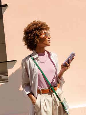 Woman standing outside in the sun holding her phone