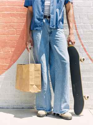 Person holding a shopping bag and skateboard