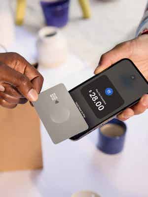 A customer pays for a purchase by tapping their card to a merchant's phone, which is equipped with Tap to Pay