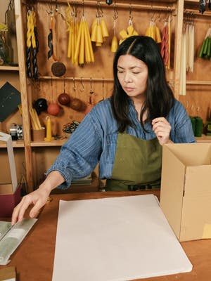 A shop owner preparing to wrap and box an item for shipping