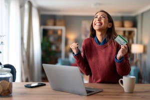 A woman happily celebrates a Cyber Monday purchase.