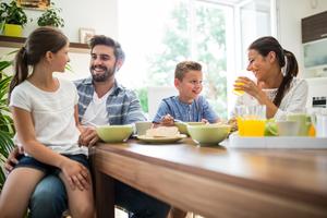 A family laughs while having breakfast together.