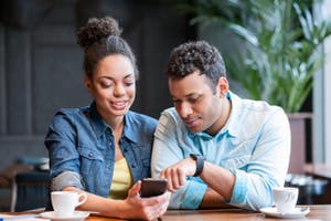 A man points out his money transfer account on a friend’s phone.