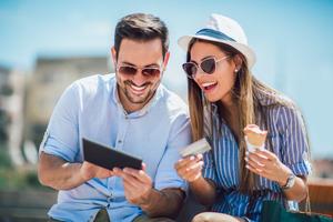 Glückliches Paar bezahlt online mit Kreditkarte, verfügbarem Kredit und digitalem Tablet auf der Straße.