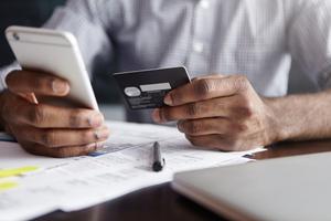 A man holds his credit card and phone to review his rewards.