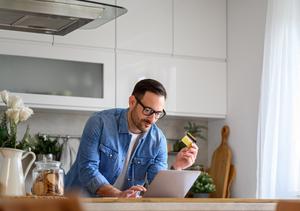 A man types his credit card information into his laptop.