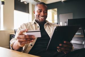 A man makes a transaction on his laptop with credit card tokenization.