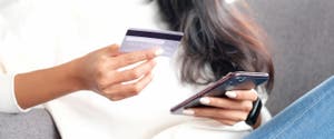 A woman reads her credit card details as she checks out on her phone.