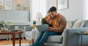 A couple reviews their savings accounts on their laptop.