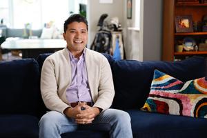 A man sits on a couch and smiles.