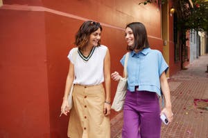 Two women stroll down the street, engaged in a lively conversation, enjoying their time together